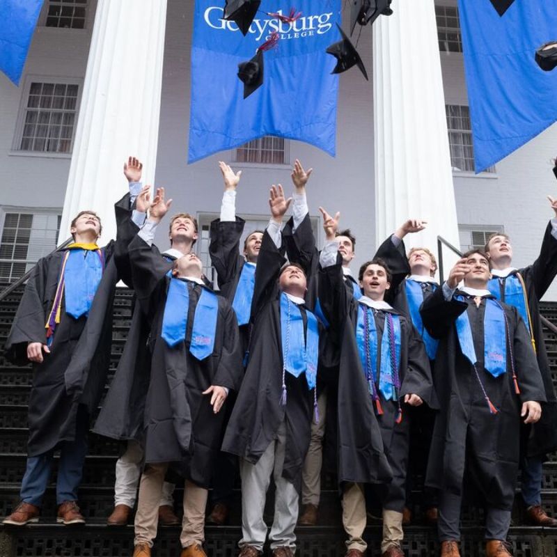 Senior student-athletes throwing their caps in the air
